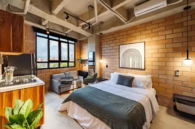 a bedroom with a bed and a brick wall at Otalu Suites in Medellín
