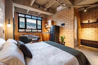 a room with a bed and a kitchen with a refrigerator at Otalu Suites in Medellín