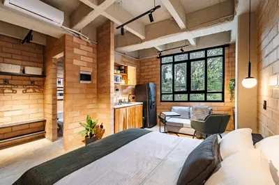 a bedroom with a large bed and a kitchen at Otalu Suites in Medellín