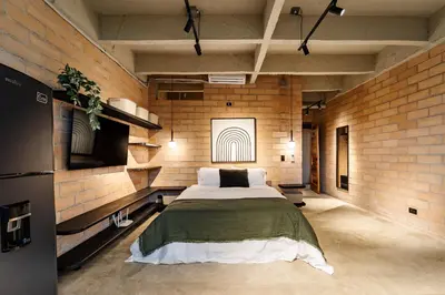 a bedroom with a large bed in a brick wall at Otalu Suites in Medellín