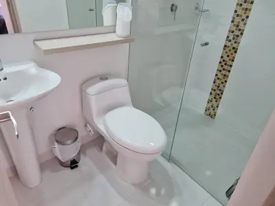 a white bathroom with a toilet and a shower at Selvatica 1014 in Sabaneta