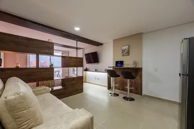 a living room with a couch and a kitchen at Apartasuite Sabaneta City view parking in Sabaneta