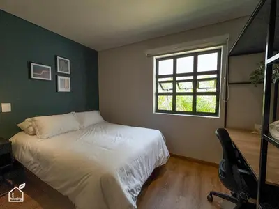 a bedroom with a white bed and a window at Ecohousing in Medellín