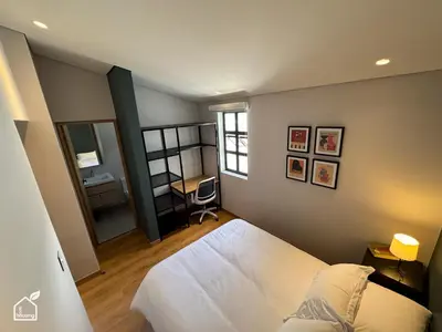 a bedroom with a white bed and a desk at Ecohousing in Medellín