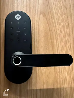 a black remote control attached to a wooden door at Ecohousing in Medellín