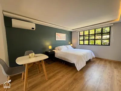 a bedroom with a bed and a table and a window at Ecohousing in Medellín