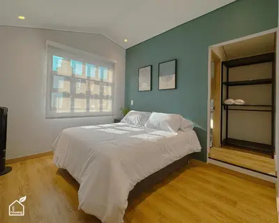 a bedroom with a large white bed with a window at Ecohousing in Medellín