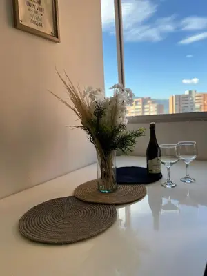 a vase with flowers on a table with wine glasses at Magnificent apartment near Lleras and Provenza in Medellín