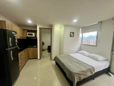 a bedroom with a bed and a kitchen with a refrigerator at Magnificent apartment near Lleras and Provenza in Medellín