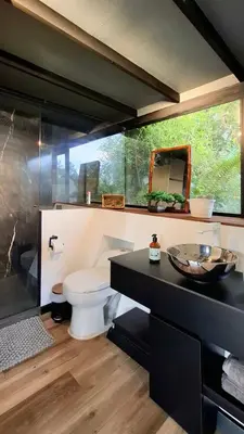 a bathroom with a toilet and a glass wall at Cabaña Del Lago - Cerca Metrocable ARVI in Guarne