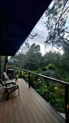 a deck with a bench and a view of the forest at Cabaña Del Lago - Cerca Metrocable ARVI in Guarne