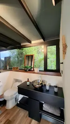 a bathroom with a toilet and a sink and a window at Cabaña en el Lago Cerca MetroCable ARVI in Guarne