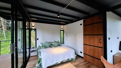 a bedroom with a bed and a large window at Cabaña en el Lago Cerca MetroCable ARVI in Guarne