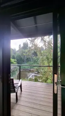 a porch with a bench and a view of a river at Cabaña en el Lago Cerca MetroCable ARVI in Guarne
