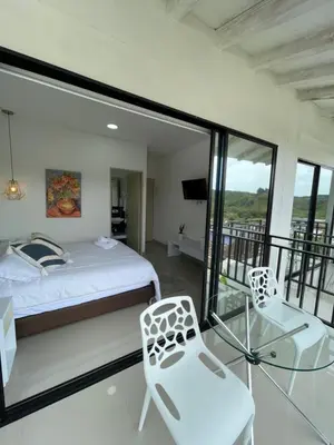 a bedroom with a bed and two chairs and a balcony at Casa Hotel Spa Carolina in Carolina del Principe