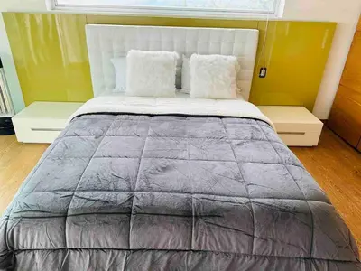 a large bed with a gray blanket and pillows at Country house near the airport and Medellin in El Retiro