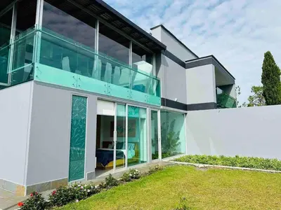 a large white house with large glass windows at Villa near the airport and Medellin in El Retiro