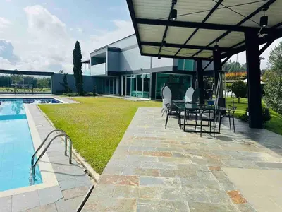 a patio with a table and chairs next to a pool at Villa near the airport and Medellin in El Retiro