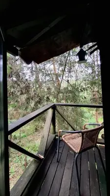 a wicker chair sitting on a wooden porch at Casa en el Arbol - Cerca Metrocable ARVI - Camping in Guarne