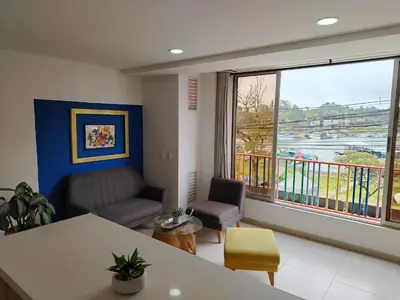 a living room with a couch and a table and a window at Frente al Malecón con Vista, Zona Gastronómica, PARQUEDERO GRATIS in Guatapé