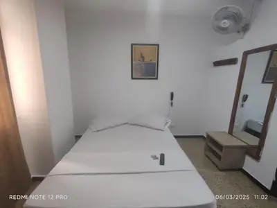 a white bed in a room with a mirror at Medellin Continental Hotel in Medellín