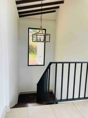 a hallway with a staircase with a window and a chandelier at 180 degree Mountain View with good size pool in Piedra El Marcial