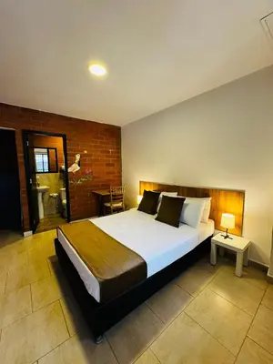 a bedroom with a large bed and a brick wall at Romeral Club Campestre in La Estrella