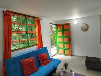 a living room with a blue couch and two windows at casa Guatape cerca al parque y malecom in Guatapé