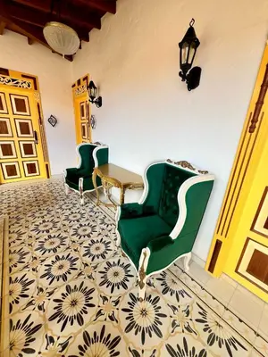 a room with two green chairs and a table at Hotel Boutique Sagrado Corazon in Abejorral