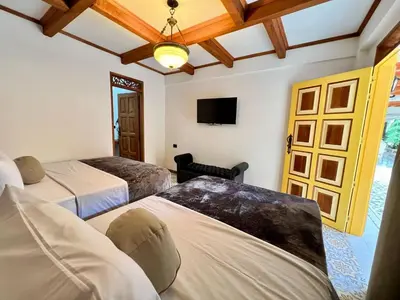 a bedroom with two beds and a tv and a room at Hotel Boutique Sagrado Corazon in Abejorral