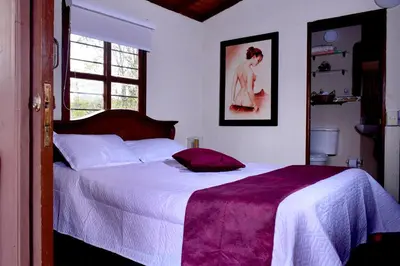 a bedroom with a large bed with a purple blanket at Finca La Concordia in Chiquinquirá