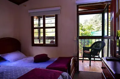 a bedroom with a bed and a chair and a window at Finca La Concordia in Chiquinquirá
