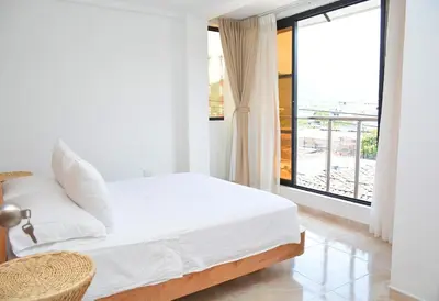 a white bedroom with a bed and a large window at Hummingbird in Chinchiná