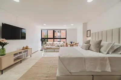 a white bedroom with a large bed and a couch at 41 Experience Laureles in style and comfort in Medellín