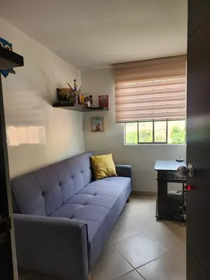a blue couch in a living room with a window at Habitación con sofacama - apto compartido in Envigado