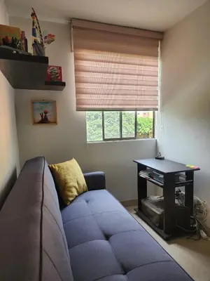 a living room with a blue couch in front of a window at Habitación con sofacama - apto compartido in Envigado