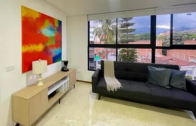 a living room with a black couch and a painting at 42 Modern Loft Top Location Laureles Medellín in Medellín