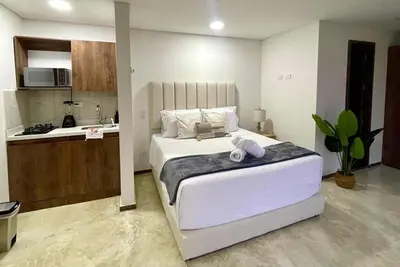 a bedroom with a large bed and a kitchen at 43 Laureles Life I Modern Loft and Excellent Location in Medellín