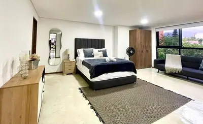 a bedroom with a bed and a living room at 44 Laureles I Medellín - Modern Loft - Céntrico y excelente ubicación in Medellín