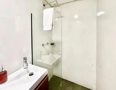 a white bathroom with a sink and a shower at 44 Laureles I Medellín - Modern Loft - Céntrico y excelente ubicación in Medellín