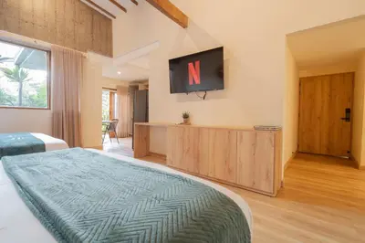 a bedroom with a bed and a tv on the wall at Candelaria Aparta Hotel Boutique in Medellín