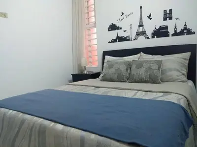 a bedroom with a bed with a blue blanket and the eiffel tower at Apto 2 alcobas 2 baños 2 closet 2 camas dobles barrio cabañitas in Bello