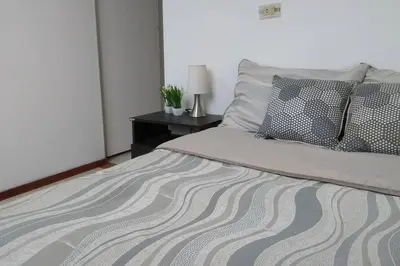a bed with pillows and a table with a lamp at Apto 2 alcobas 2 baños 2 closet 2 camas dobles barrio cabañitas in Bello