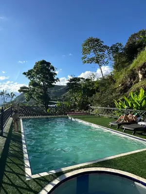 a swimming pool in a resort with people laying on the grass at Glamping Mirador El Tunel in Estación El Salto
