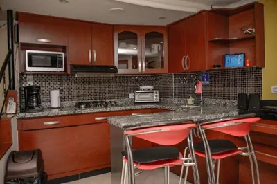 a kitchen with wooden cabinets and red bar stools at Calle 10 Suites in Medellín