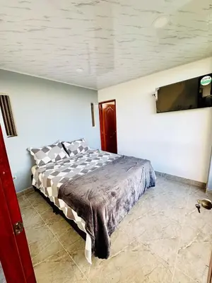 a bedroom with a bed and a tv on the wall at Hermosa Cabaña en El Peñol in Chiquinquirá