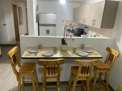 a kitchen with a table with chairs and plates on it at Hermoso y cómodo apartamento 4 habitaciones cerca al Viva Envigado in Envigado