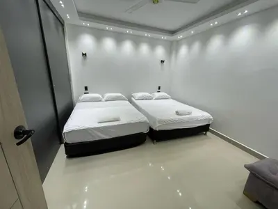 a bedroom with two beds in a white room at Class Suite Apartamento Doradal in Doradal
