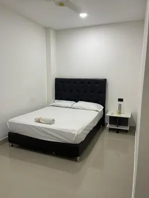 a bedroom with a large bed with a black headboard at Class Suite Apartamento Doradal in Doradal