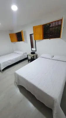 a white bedroom with two beds and a window at Villa Andrea Apartamento de lujo en Jericó Antioquia para 7 personas in Jericó
